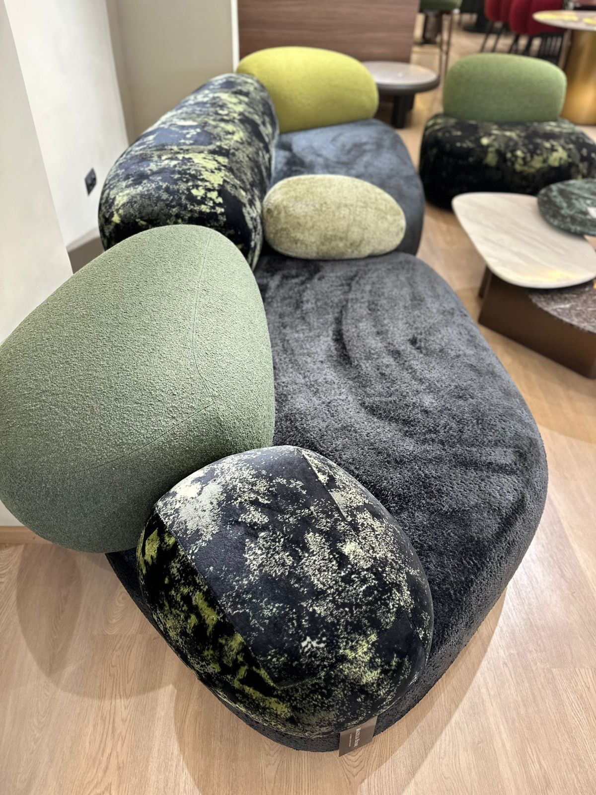 Canapé design aux formes arrondies avec dossier et coussins moelleux, inspiré d’un style contemporain et organique, placé dans un intérieur moderne.