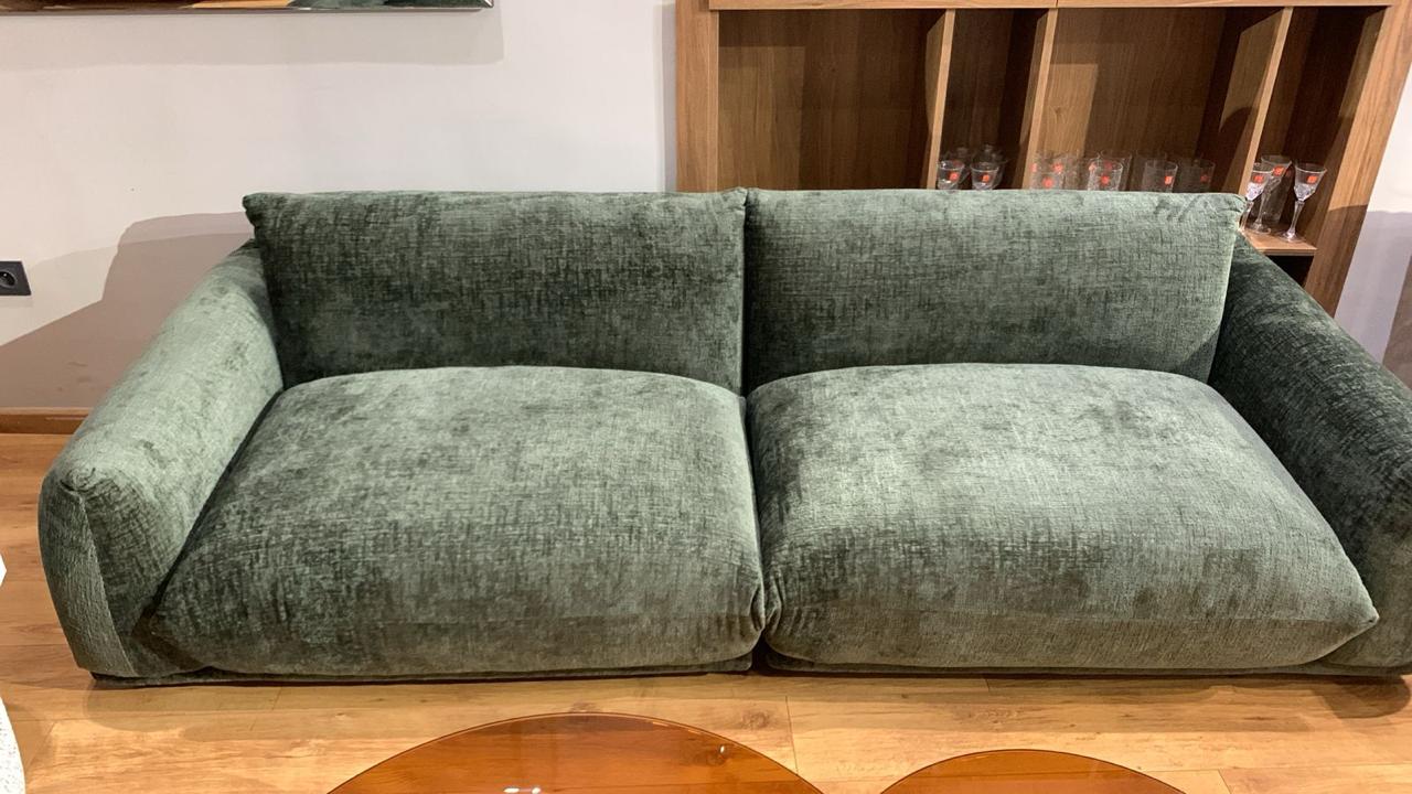 Canapé en velours chiné vert avec des accoudoirs larges et assise profonde.