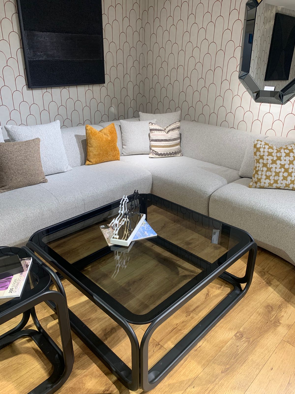 Grand canapé d’angle aux lignes arrondies en tissu bouclé , décoré de plusieurs coussins colorés.