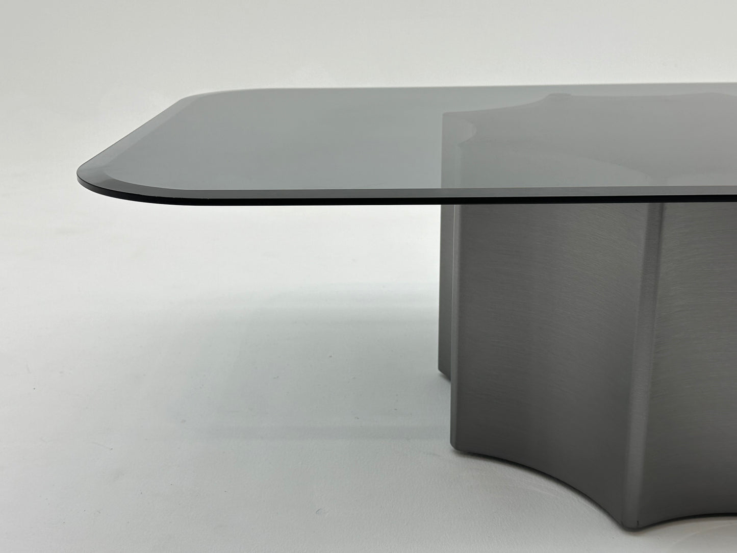Table basse moderne avec plateau en verre fumé et base en métal solide. Un design minimaliste qui combine élégance et robustesse.