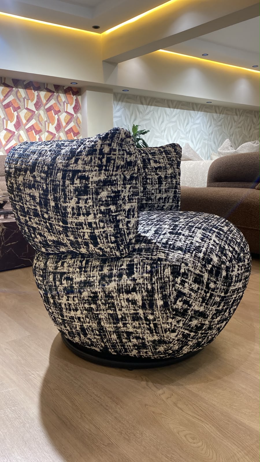 Bergère contemporaine arrondie avec assise confortable et base pivotante, revêtement en tissu texturé.