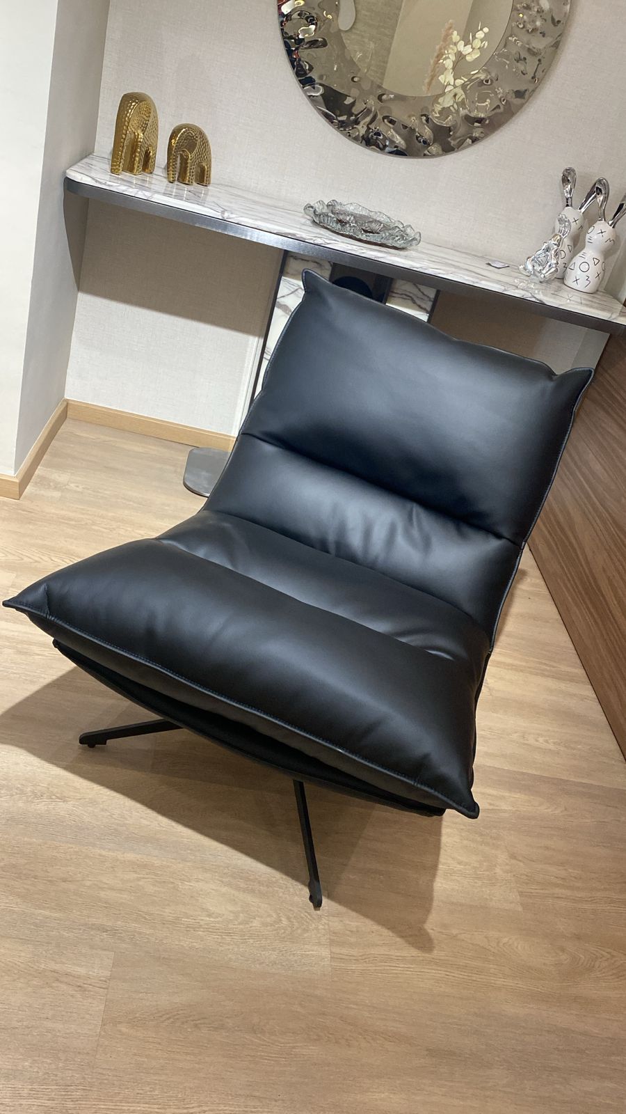 Bergère moderne noire en similicuir avec structure métallique élégante pour salon contemporain.