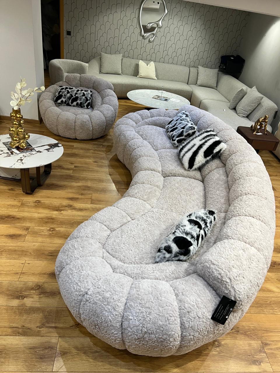 Canapé design organique en tissu bouclé beige avec formes arrondies et assise profonde pour salon moderne.