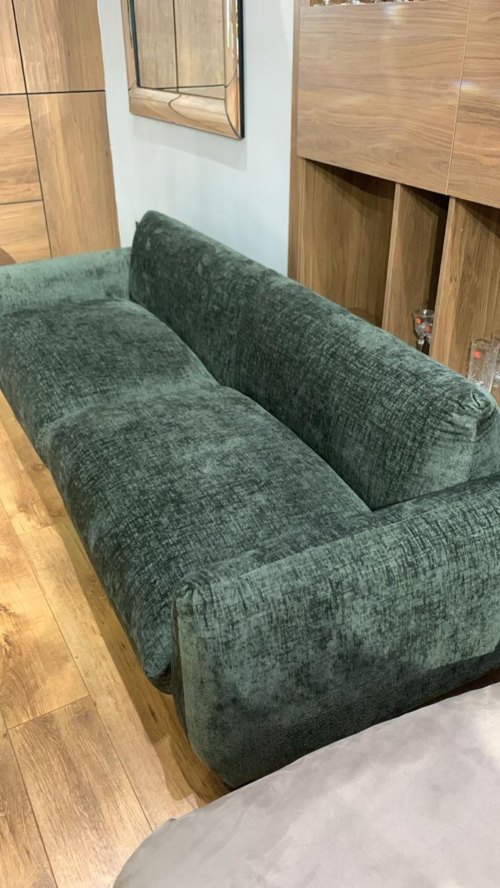 Canapé en velours chiné vert avec des accoudoirs larges et assise profonde.