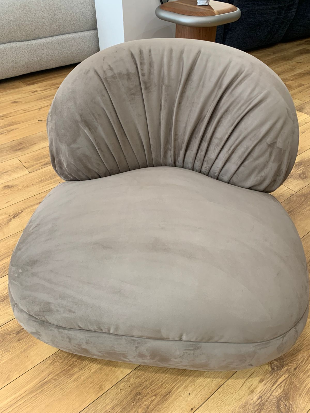 Fauteuil bergère au design arrondi en velours , avec un dossier plissé.