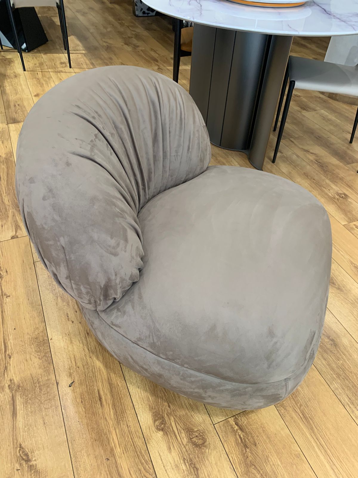 Fauteuil bergère au design arrondi en velours , avec un dossier plissé.