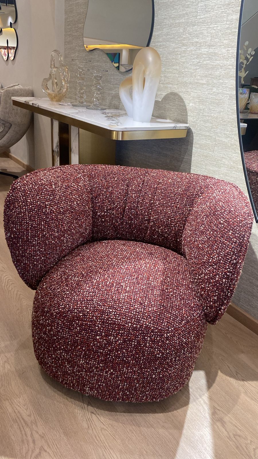 Fauteuil bergère moderne en tissu bouclé rouge rubis avec dossier arrondi et assise confortable, idéal pour un salon contemporain et élégant.