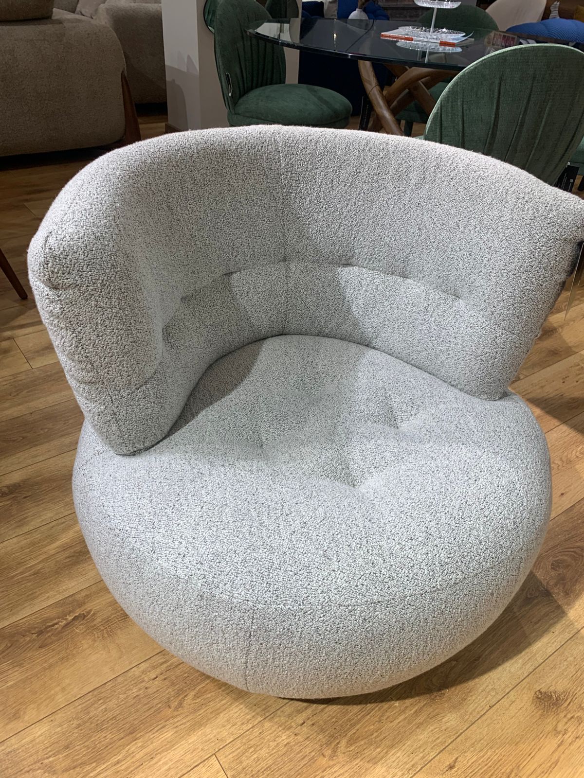 Fauteuil bergère arrondi gris clair en tissu bouclette, dossier enveloppant et assise profonde, style contemporain pour coin détente .