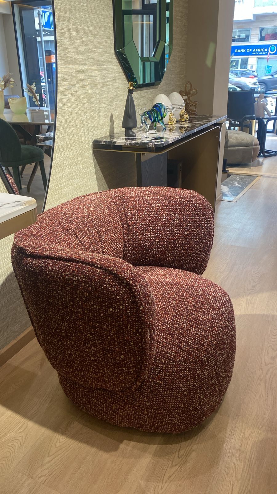 Fauteuil bergère moderne en tissu bouclé rouge rubis avec dossier arrondi et assise confortable, idéal pour un salon contemporain et élégant.