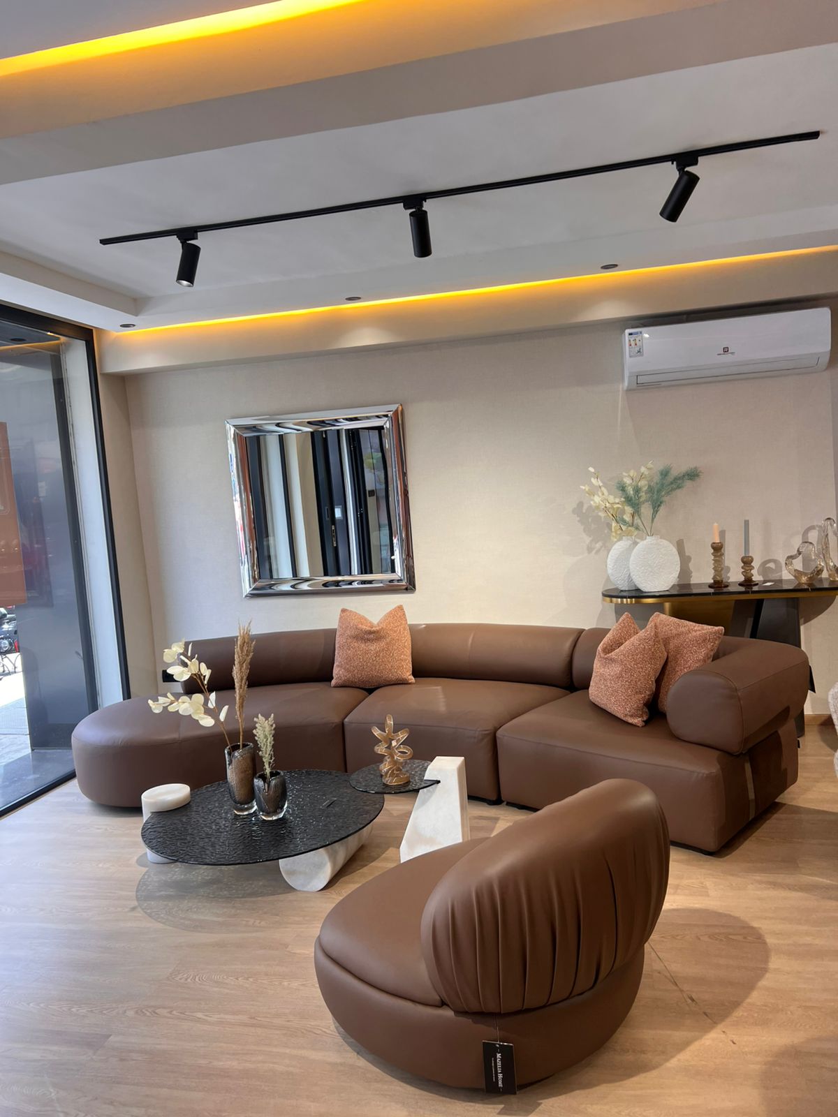 Canapé moderne en cuir marron 100 %, design arrondi et élégant,  dans un salon contemporain lumineux .