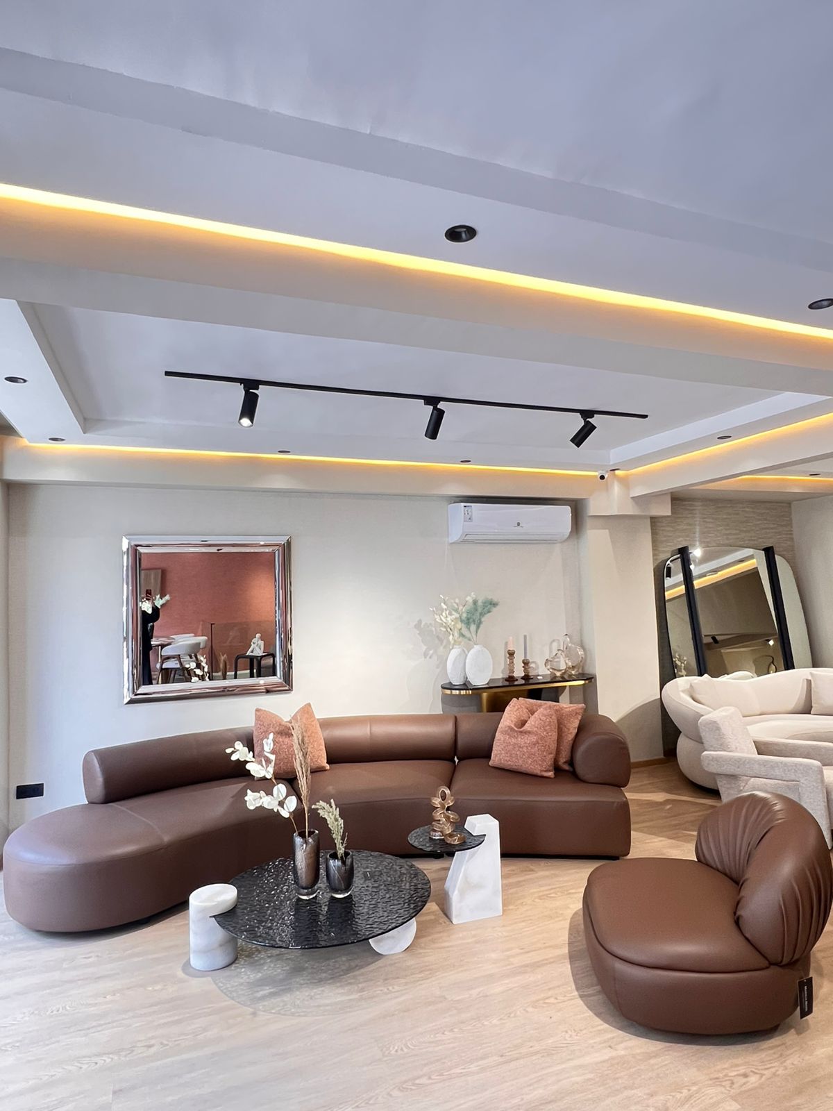 Canapé moderne en cuir marron 100 %, design arrondi et élégant,  dans un salon contemporain lumineux .
