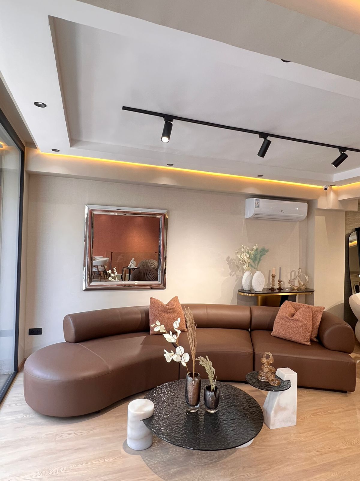 Canapé moderne en cuir marron 100 %, design arrondi et élégant,  dans un salon contemporain lumineux .