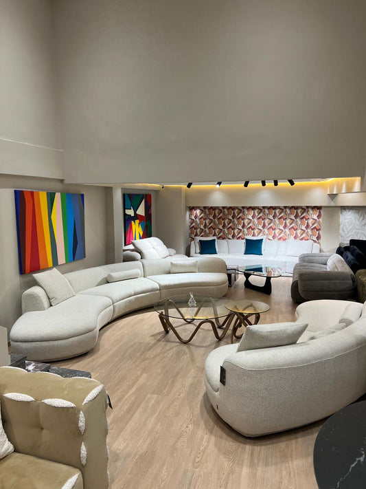 Canapé design aux formes organiques, revêtu d’un tissu clair, avec assise profonde et courbes modernes, présenté dans un salon contemporain.