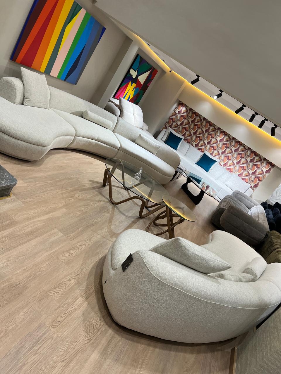 Canapé design aux formes organiques, revêtu d’un tissu clair, avec assise profonde et courbes modernes, présenté dans un salon contemporain.