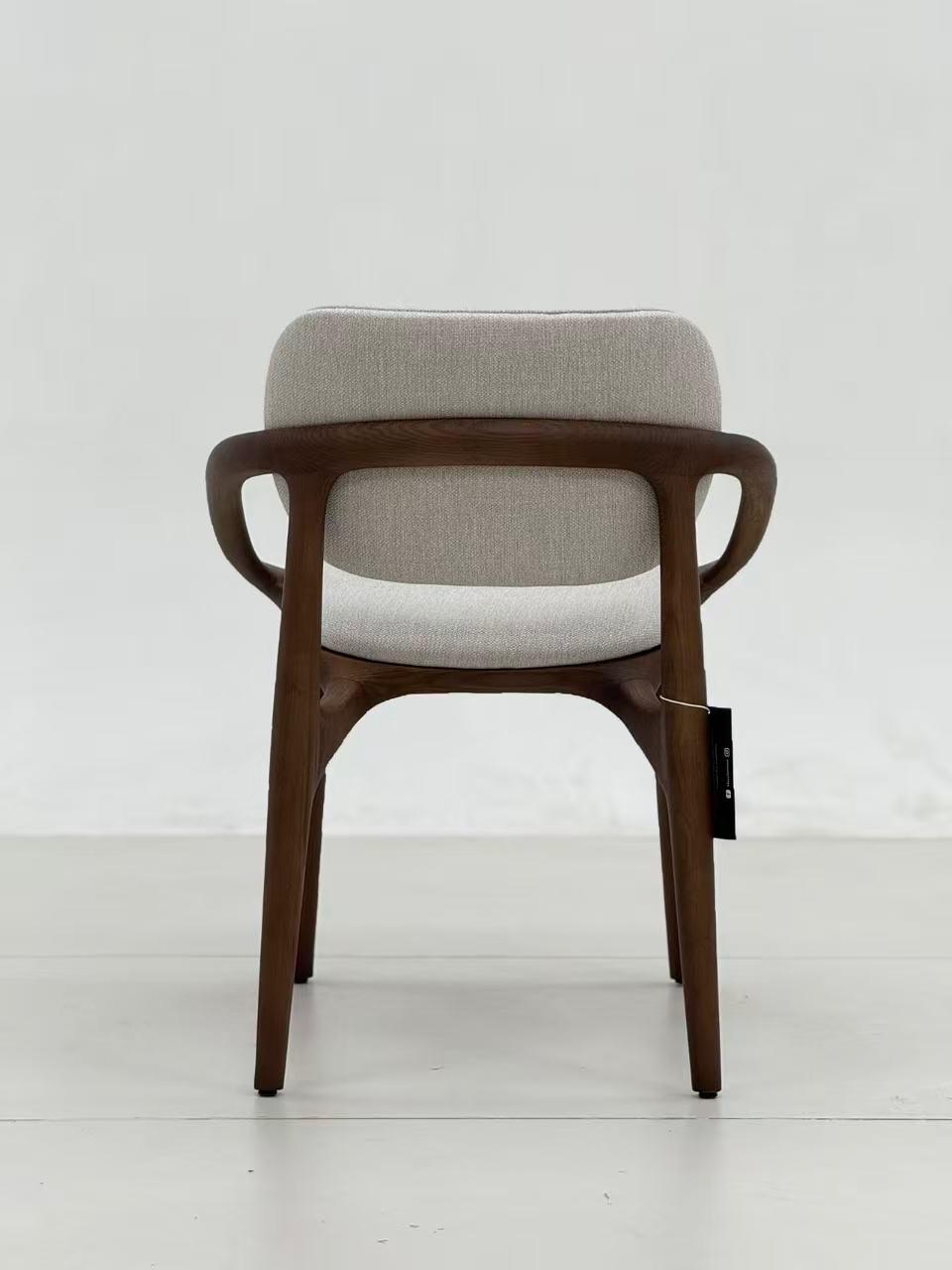 Chaise design en bois foncé avec accoudoirs, assise et dossier rembourrés en tissu clair, au style moderne et élégant.