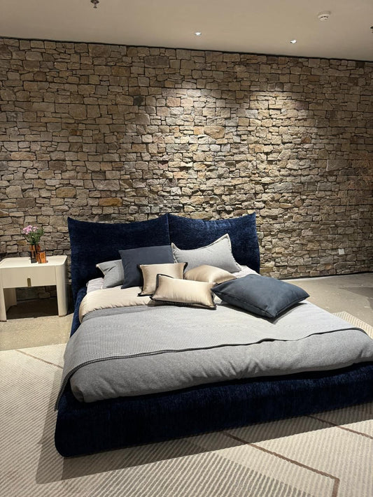 Lit moderne bas avec tête de lit rembourrée en tissu bleu, style contemporain.