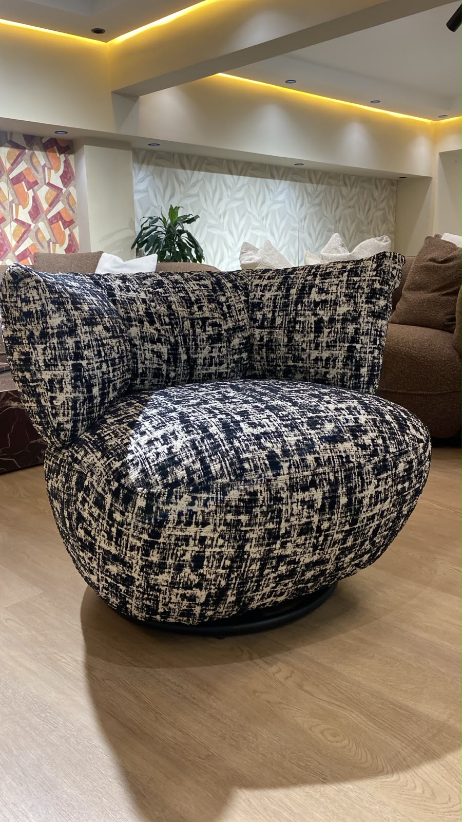 Bergère contemporaine arrondie avec assise confortable et base pivotante, revêtement en tissu texturé.
