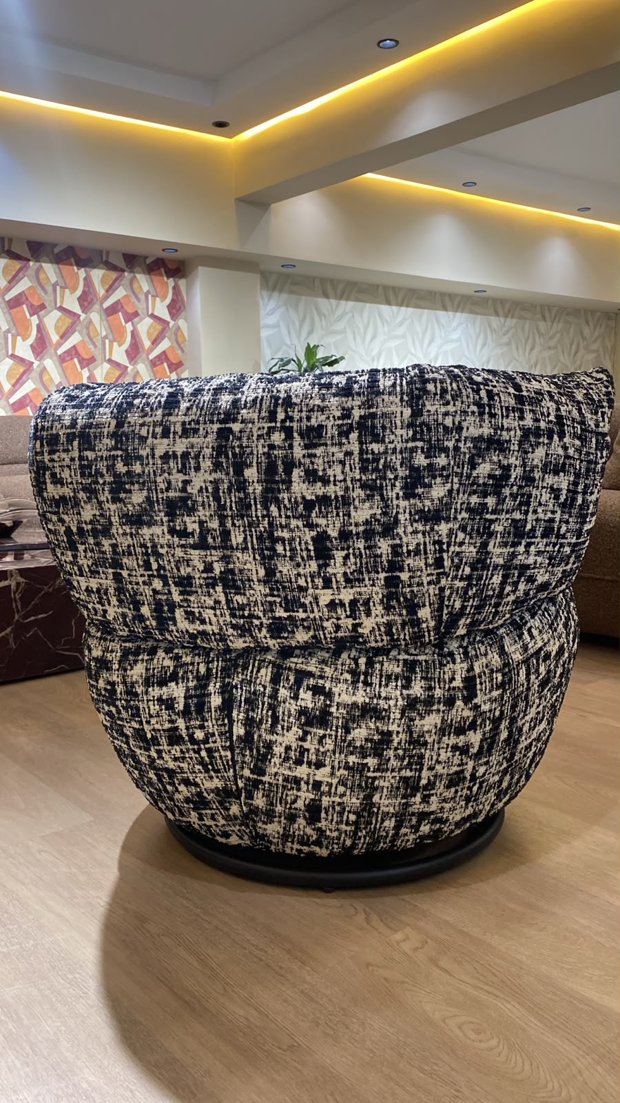 Bergère contemporaine arrondie avec assise confortable et base pivotante, revêtement en tissu texturé.