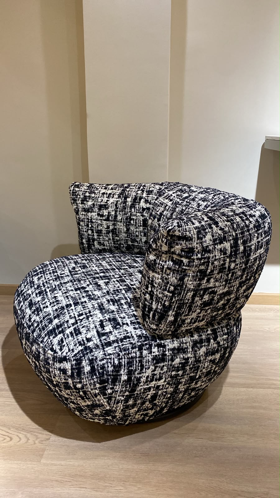 Bergère contemporaine arrondie avec assise confortable et base pivotante, revêtement en tissu texturé.