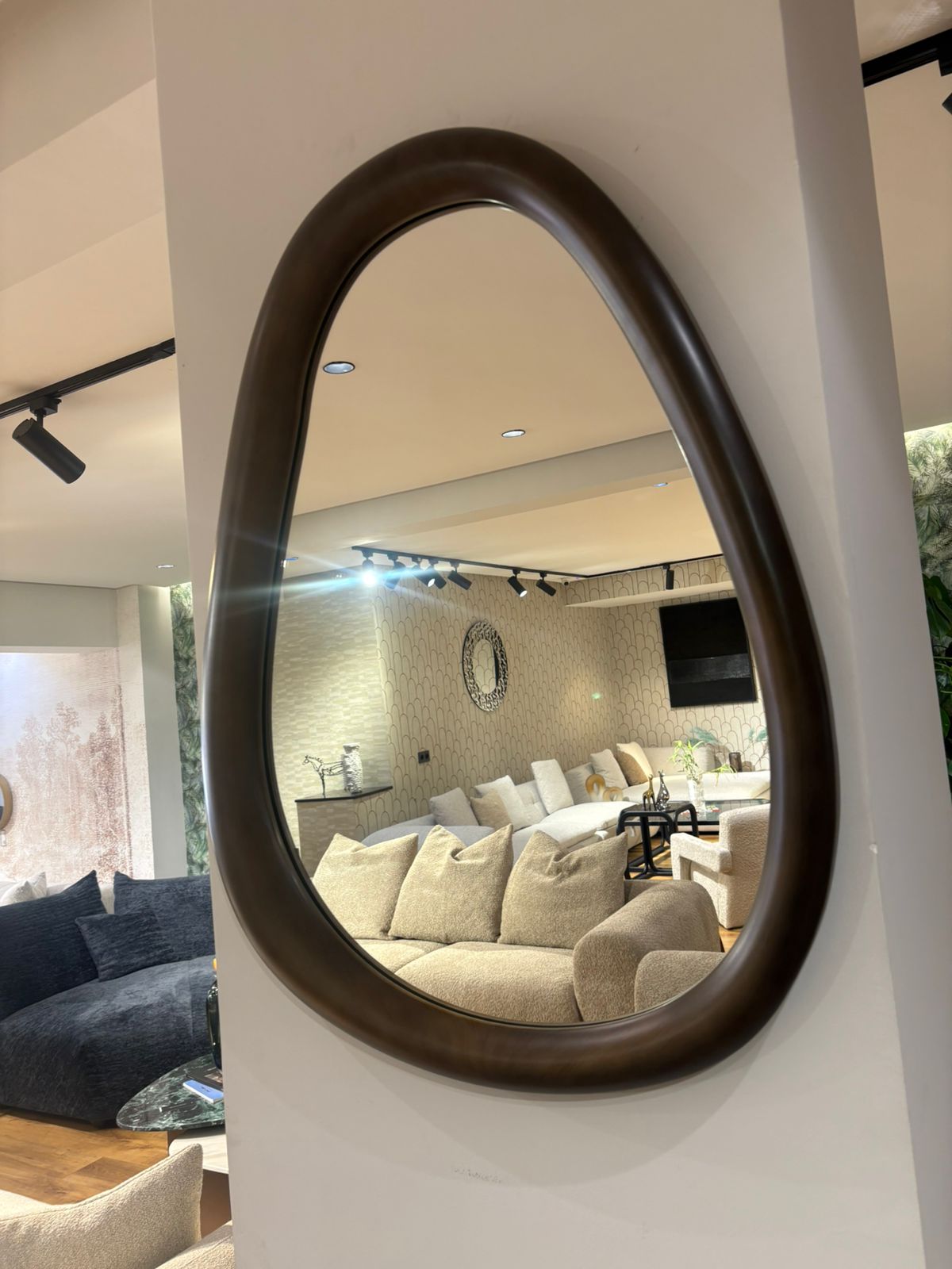 Miroir mural design forme organique avec cadre en bois marron épais dans un intérieur moderne