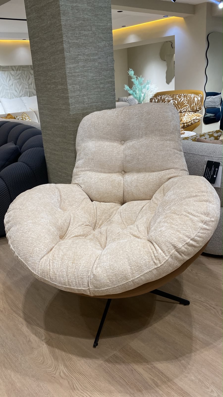 Bergère contemporaine avec assise moelleuse, dossier enveloppant et piètement pivotant en métal, idéale pour un salon moderne.