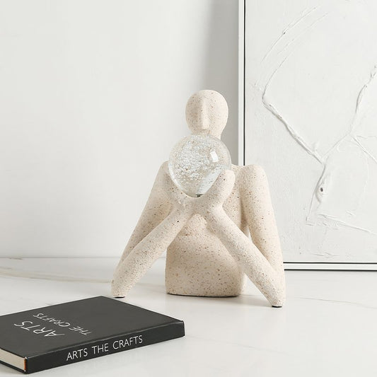 Sculpture décorative moderne représentant une silhouette minimaliste en pierre tenant une sphère en verre transparente,