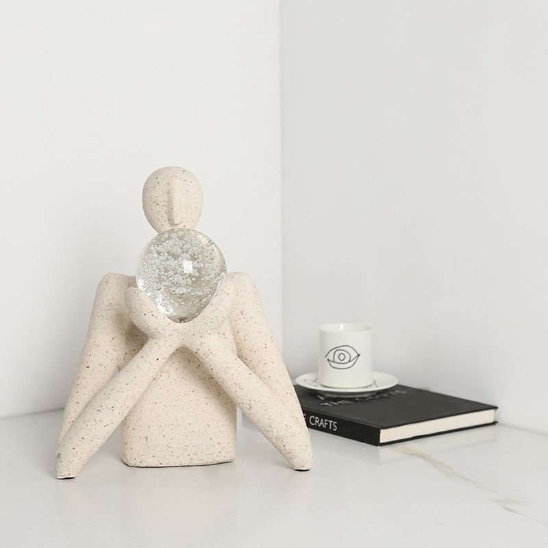 Sculpture décorative moderne représentant une silhouette minimaliste en pierre tenant une sphère en verre transparente,
