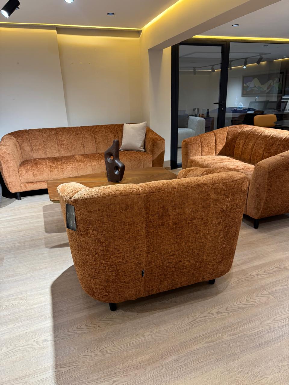 Salon moderne en tissu texturé , composé de deux canapés et d’un fauteuil aux formes arrondies, offrant un design contemporain et un confort élégant.