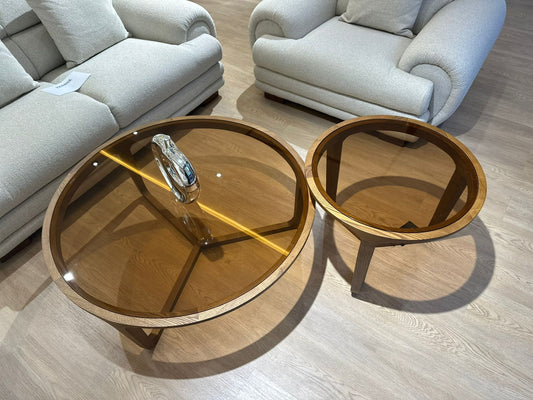 Ensemble rondes en bois de noyer avec plateau en verre teinté ambré, design moderne, placées dans un salon contemporain.