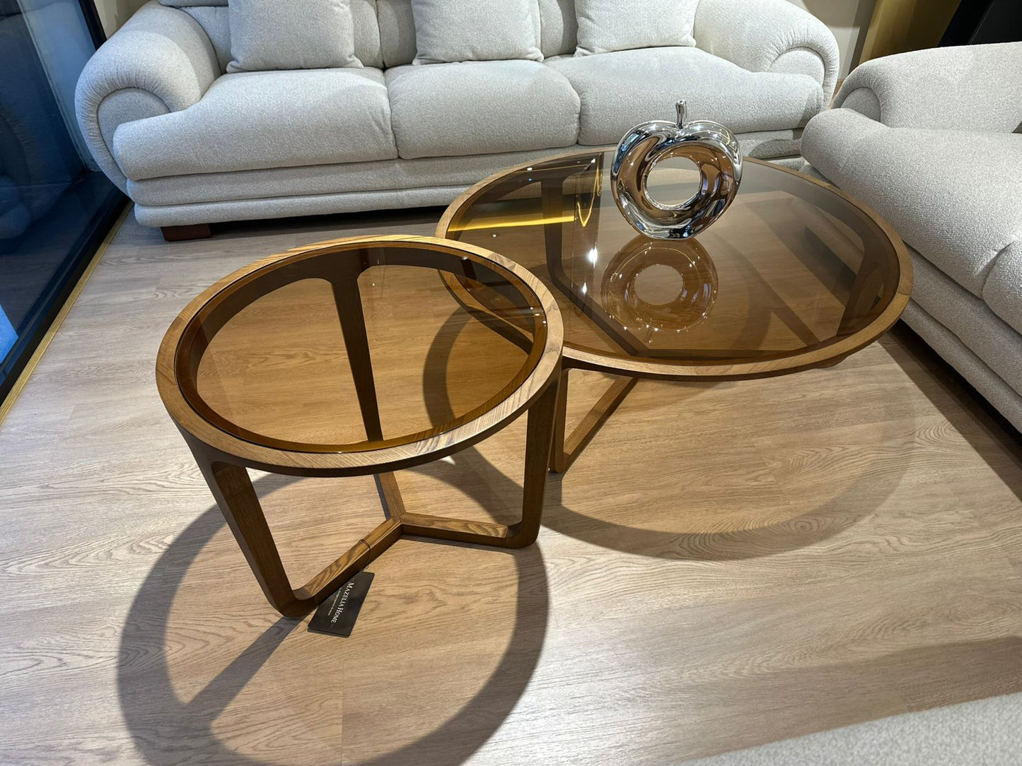 Ensemble rondes en bois de noyer avec plateau en verre teinté ambré, design moderne, placées dans un salon contemporain