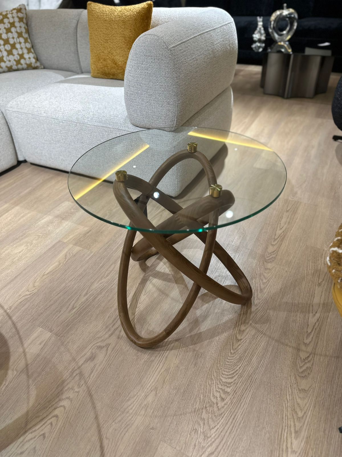 Table basse design avec plateau en verre rond et structure sculpturale en bois courbé, accompagnée d’une table d’appoint assortie.