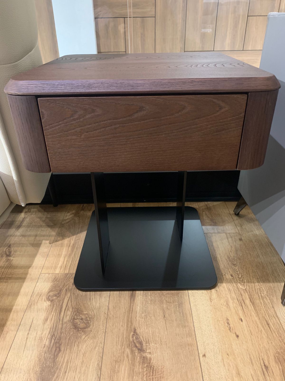 Table de chevet moderne en bois foncé avec tiroir et piètement central en métal noir, au design minimaliste et élégant.