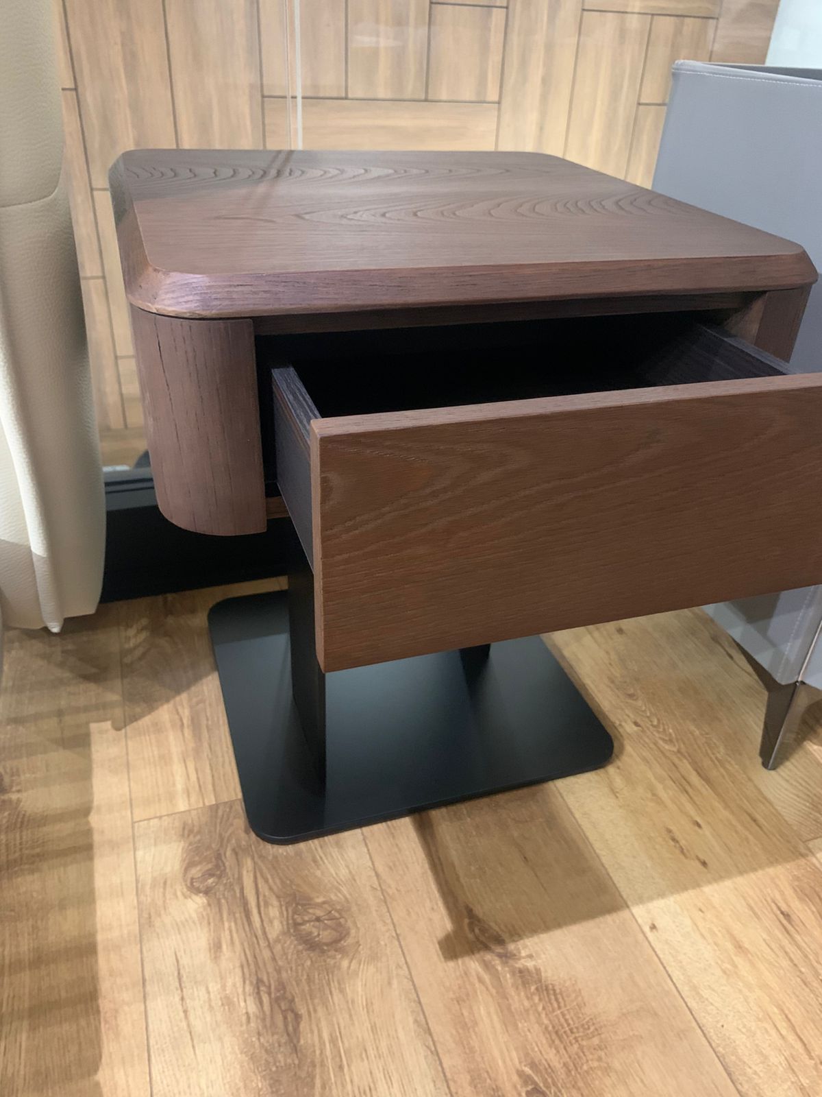 Table de chevet moderne en bois foncé avec tiroir et piètement central en métal noir, au design minimaliste et élégant.
