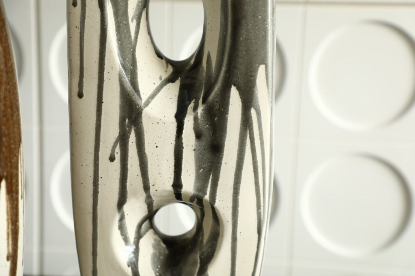 Vase décoratif moderne en céramique noir et ivoire avec design sculptural ajouré.