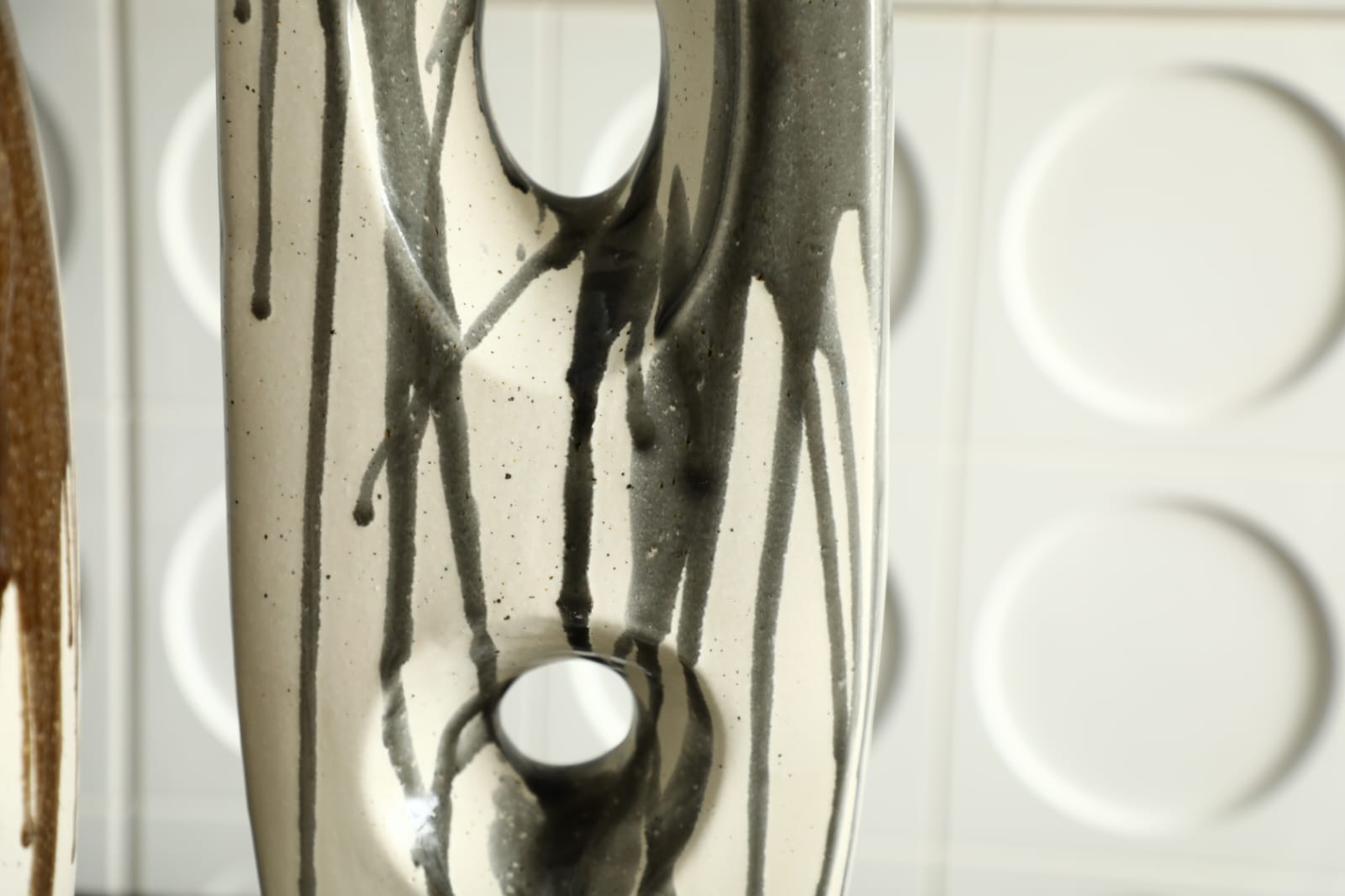 Vase décoratif moderne en céramique noir et ivoire avec design sculptural ajouré.