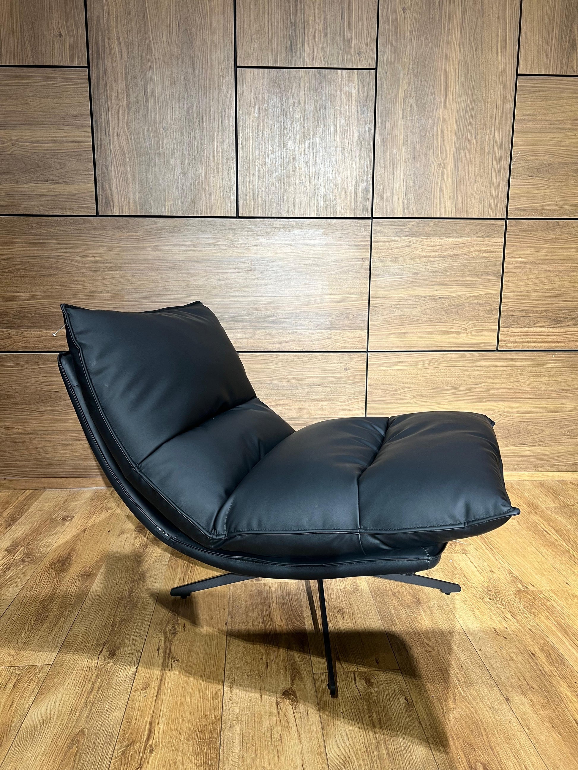 Bergère moderne noire en similicuir avec structure métallique élégante pour salon contemporain.