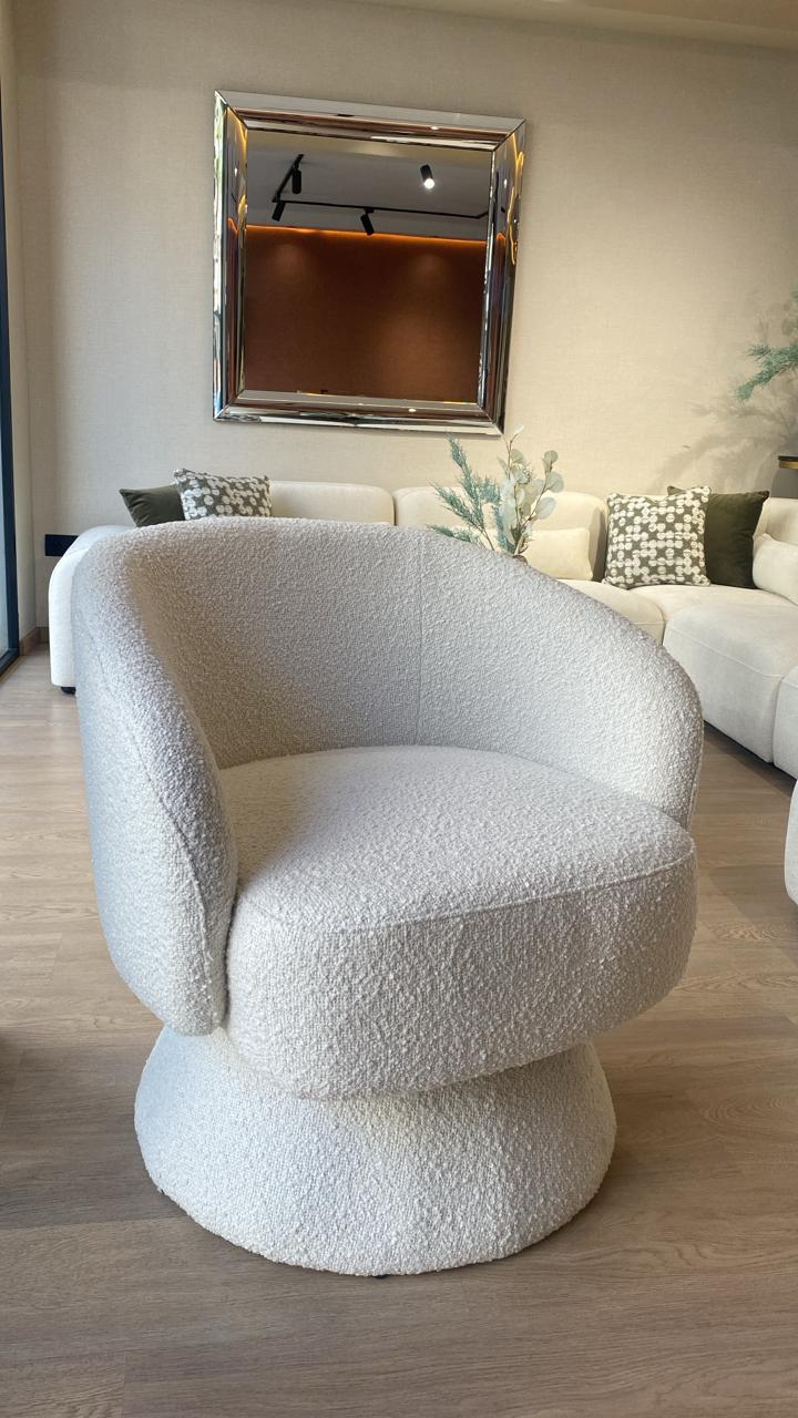 Fauteuil bergère moderne en tissu bouclette blanc avec base pivotante, design arrondi élégant et assise confortable pour salon contemporain.