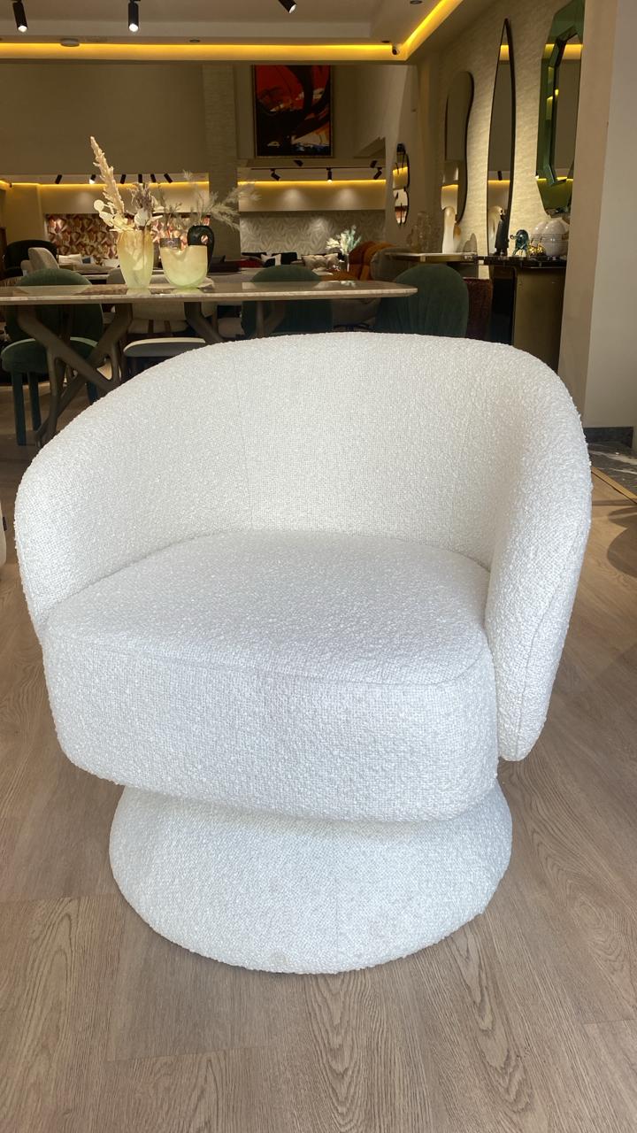 Fauteuil bergère moderne en tissu bouclette blanc avec base pivotante, design arrondi élégant et assise confortable pour salon contemporain.