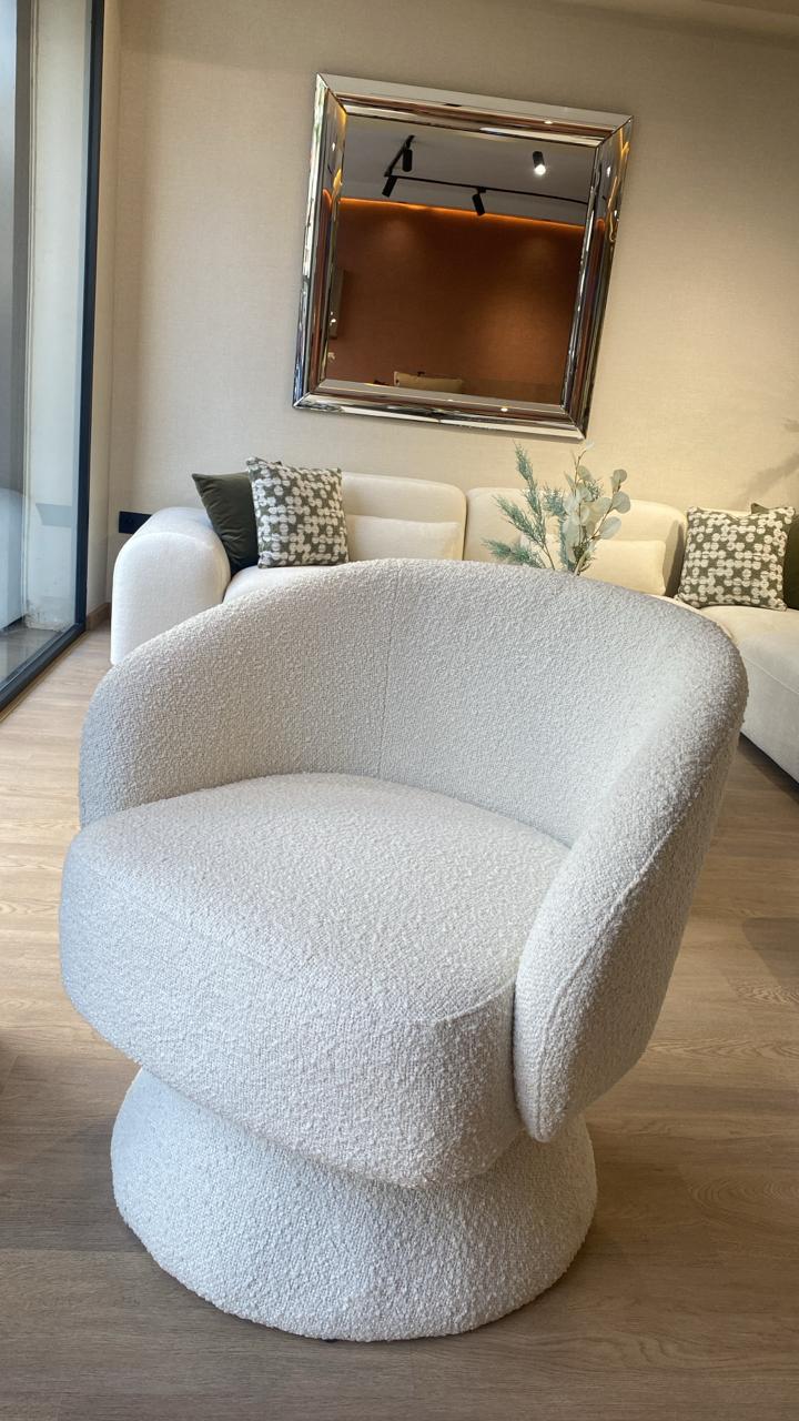 Fauteuil bergère moderne en tissu bouclette blanc avec base pivotante, design arrondi élégant et assise confortable pour salon contemporain.