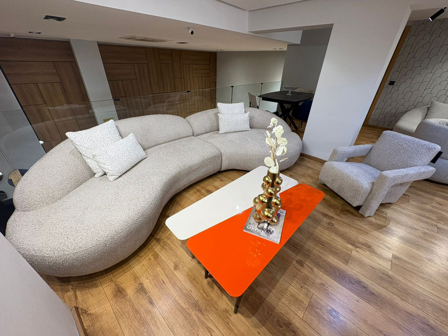 Canapé design arrondi en tissu beige avec fauteuils assortis dans un salon moderne lumineux