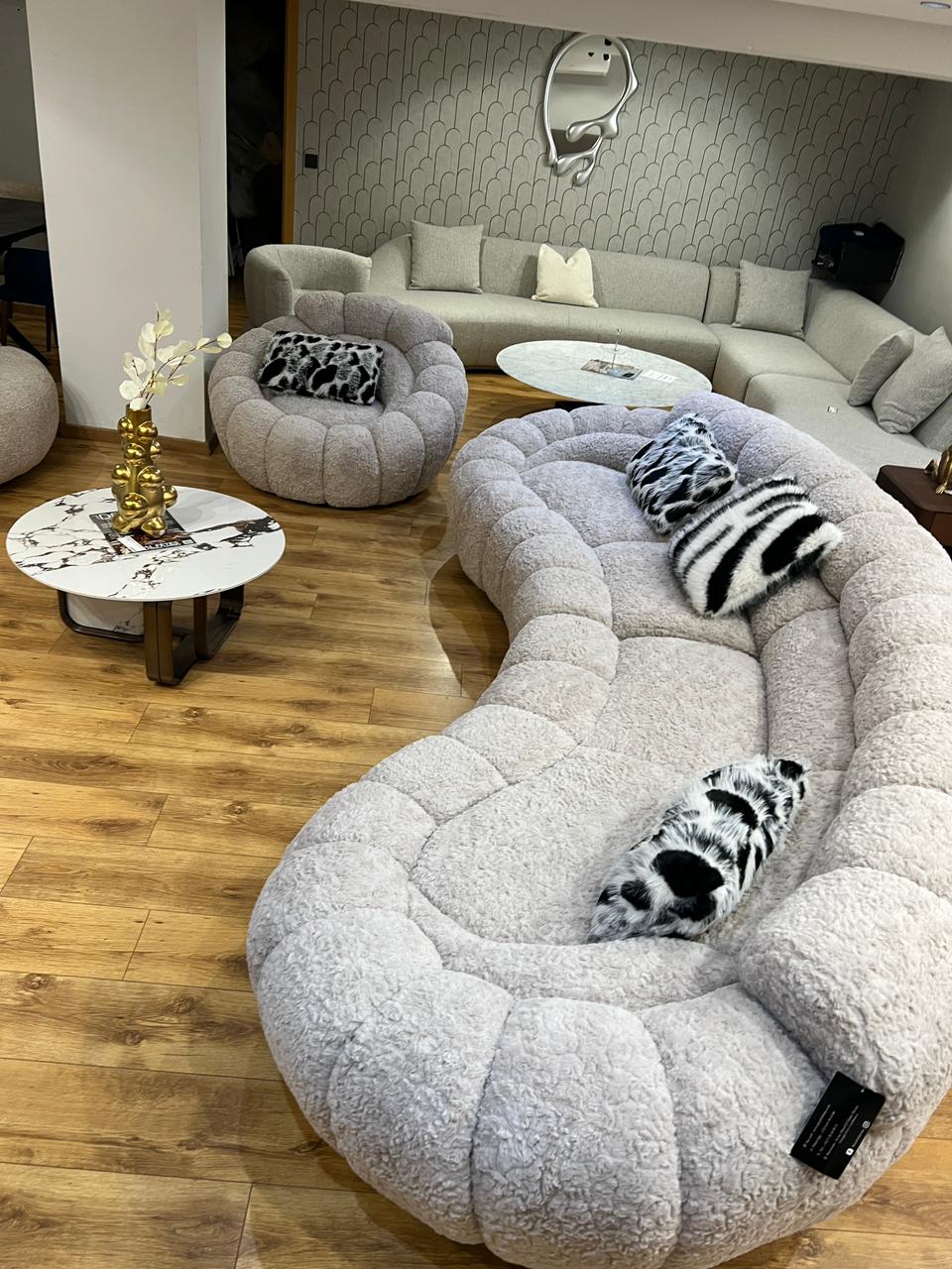 Canapé design organique en tissu bouclé beige avec formes arrondies et assise profonde pour salon moderne.