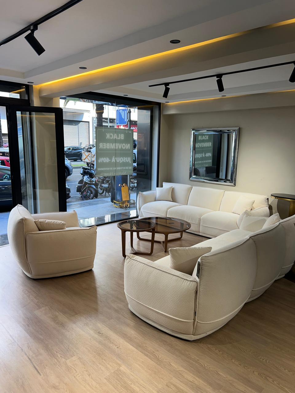 Salon moderne en tissu blanc cassé avec deux canapés et un fauteuil assorti dans un intérieur lumineux et épuré. 