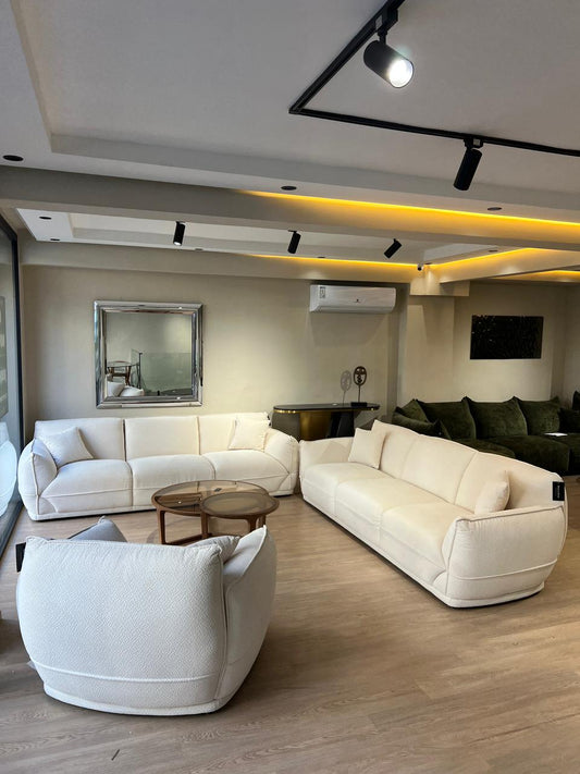 Salon moderne en tissu blanc cassé  avec deux canapés  et un fauteuil assorti dans un intérieur lumineux et épuré.