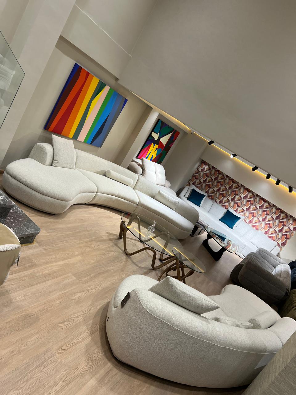 Canapé design aux formes organiques, revêtu d’un tissu clair, avec assise profonde et courbes modernes, présenté dans un salon contemporain.