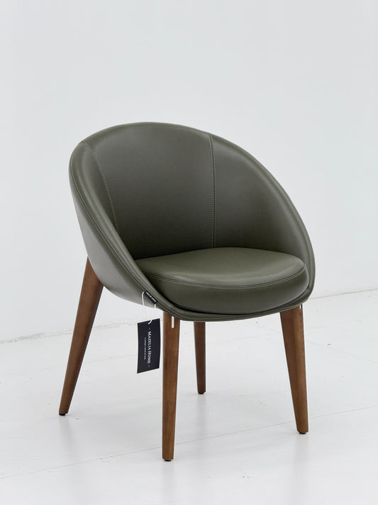Chaise moderne vert olive en similicuir avec pieds en bois massif, design enveloppant et assise confortable pour salle à manger ou bureau.