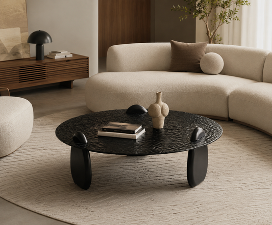 Table basse ronde au design sculptural avec plateau texturé et pieds arrondis, idéale pour un salon moderne.