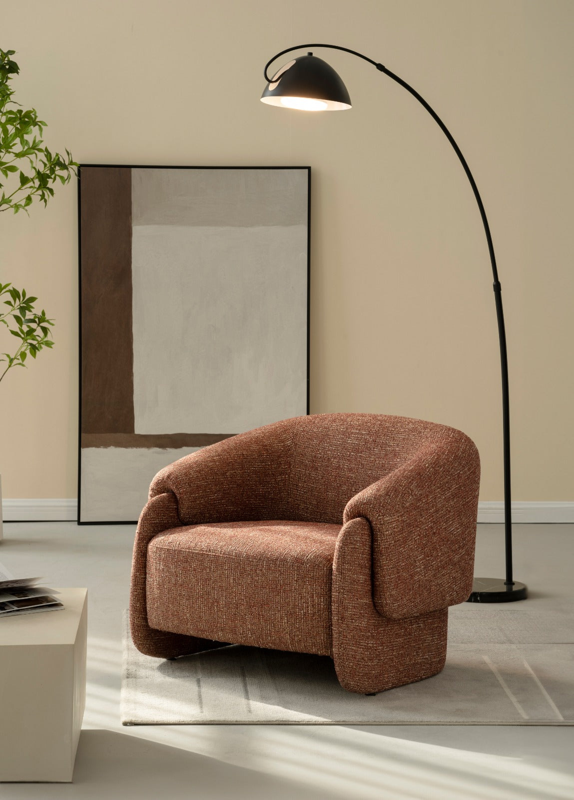 Bergère moderne en tissu avec dossier arrondi et accoudoirs enveloppants, idéale pour un salon élégant et contemporain.