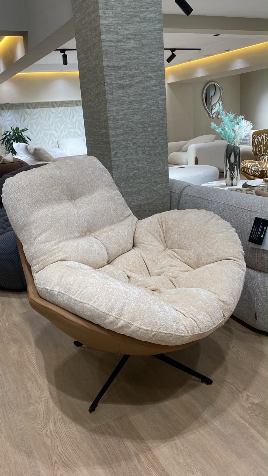 Bergère contemporaine avec assise moelleuse, dossier enveloppant et piètement pivotant en métal, idéale pour un salon moderne.