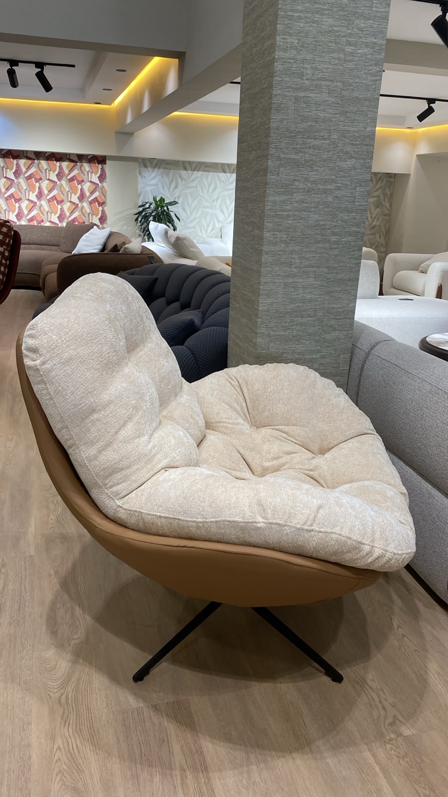 Bergère contemporaine avec assise moelleuse, dossier enveloppant et piètement pivotant en métal, idéale pour un salon moderne.