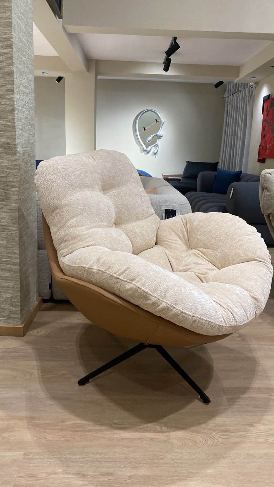 Bergère contemporaine avec assise moelleuse, dossier enveloppant et piètement pivotant en métal, idéale pour un salon moderne.